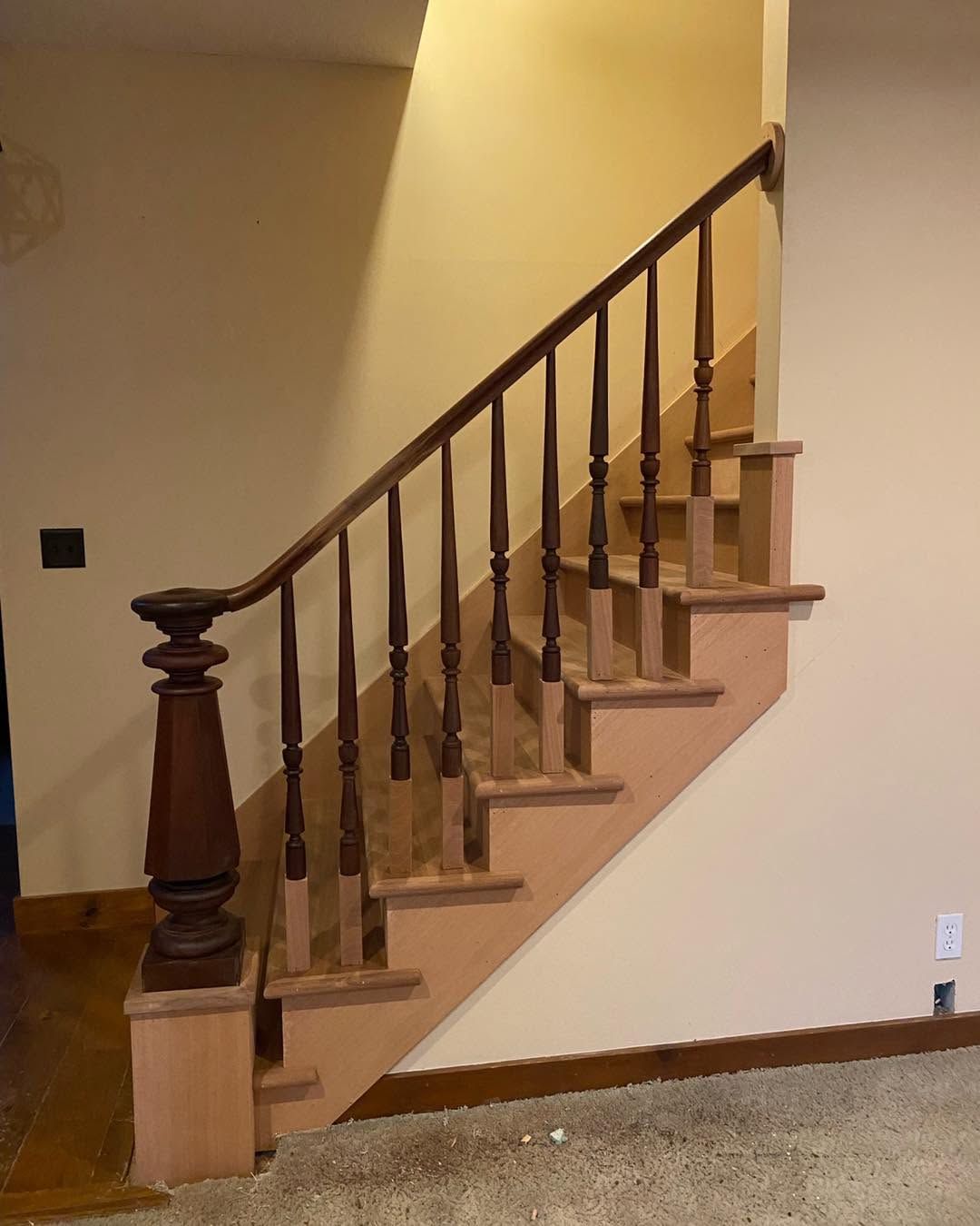 Wooden staircase with carpeted steps and dark banister in a beige interior hallway.