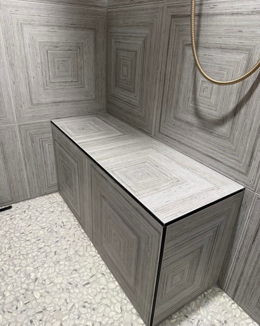 Gray geometric-tiled bathroom with a long rectangular counter and a gold chain on the wall.