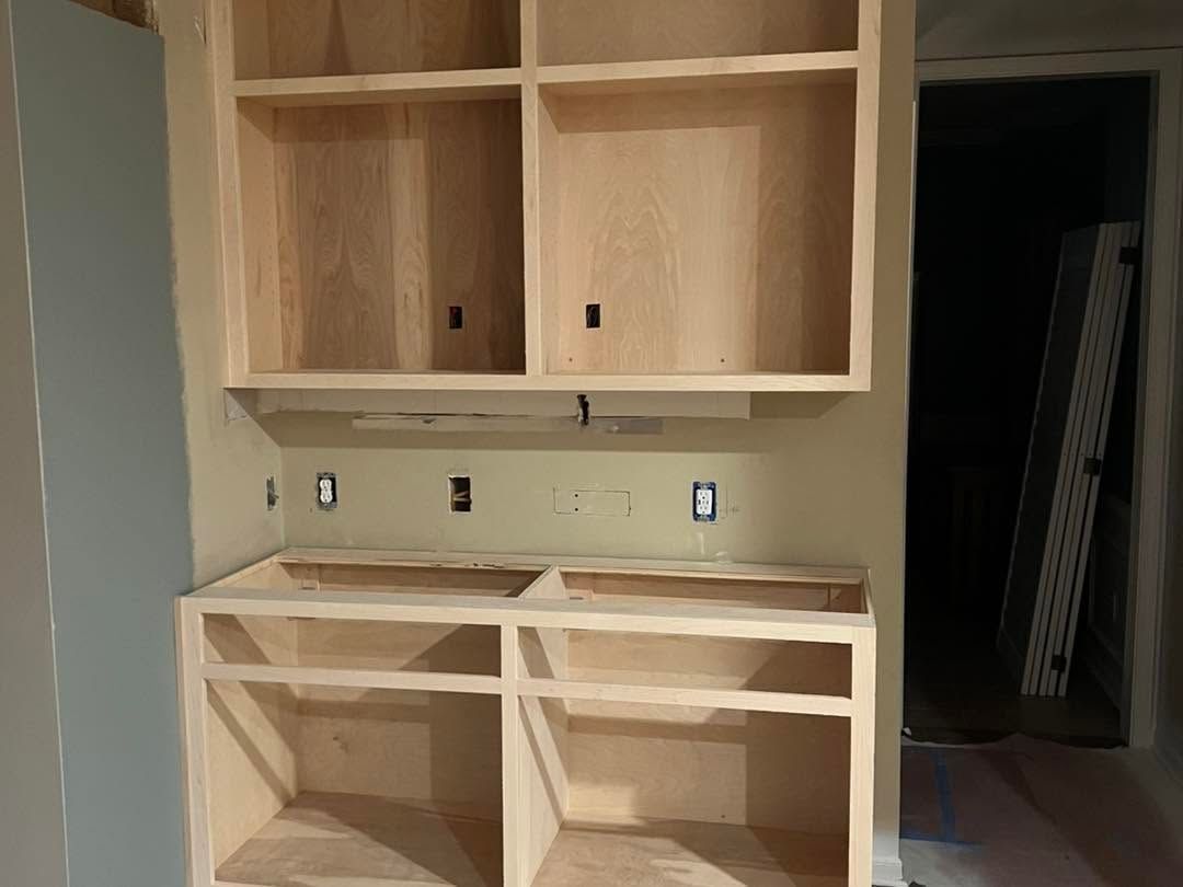 Unfinished beige kitchen cabinets and countertop with sink cutouts in a room under renovation