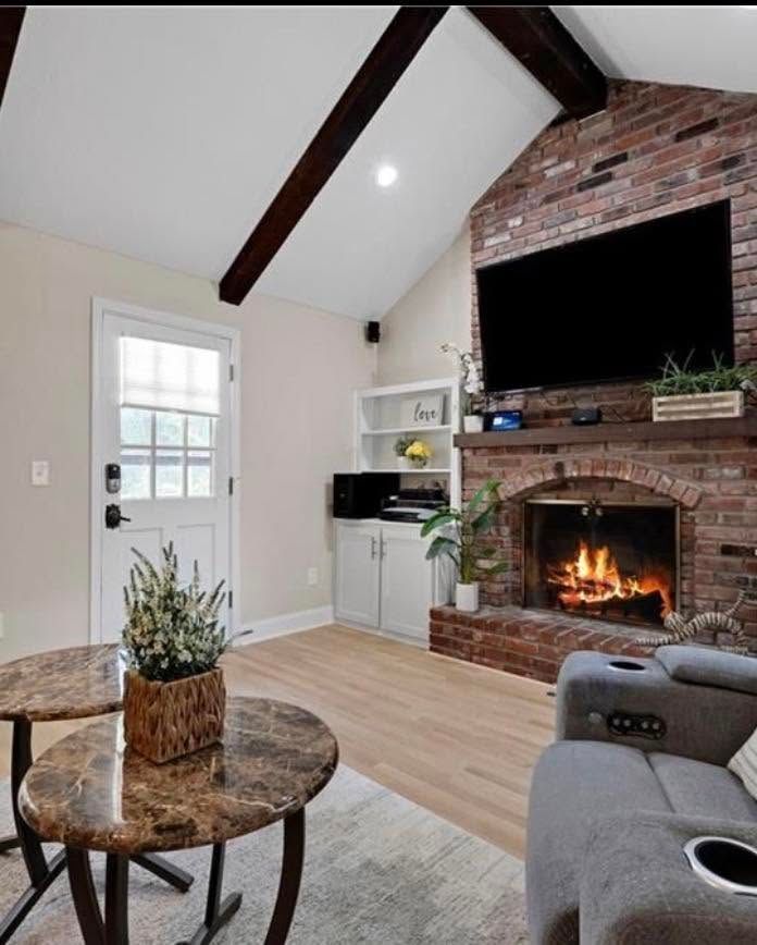 Cozy living room with vaulted ceiling, brick fireplace, gray sofa, coffee table, and TV above the mantel