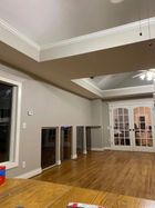 Empty living room with hardwood floors, beige walls, recessed ceiling, and French doors at the far end
