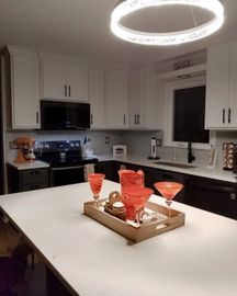 Modern white kitchen with black countertops and an island set with orange drinkware on a tray