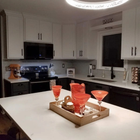 Modern white kitchen with island centerpiece and red glass decor under a circular ceiling light