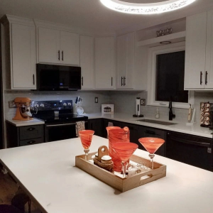 Modern white kitchen with island centerpiece and red glass decor under a circular ceiling light