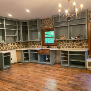 Built-in living room cabinetry with stone wall, hardwood floors, and chandelier lighting