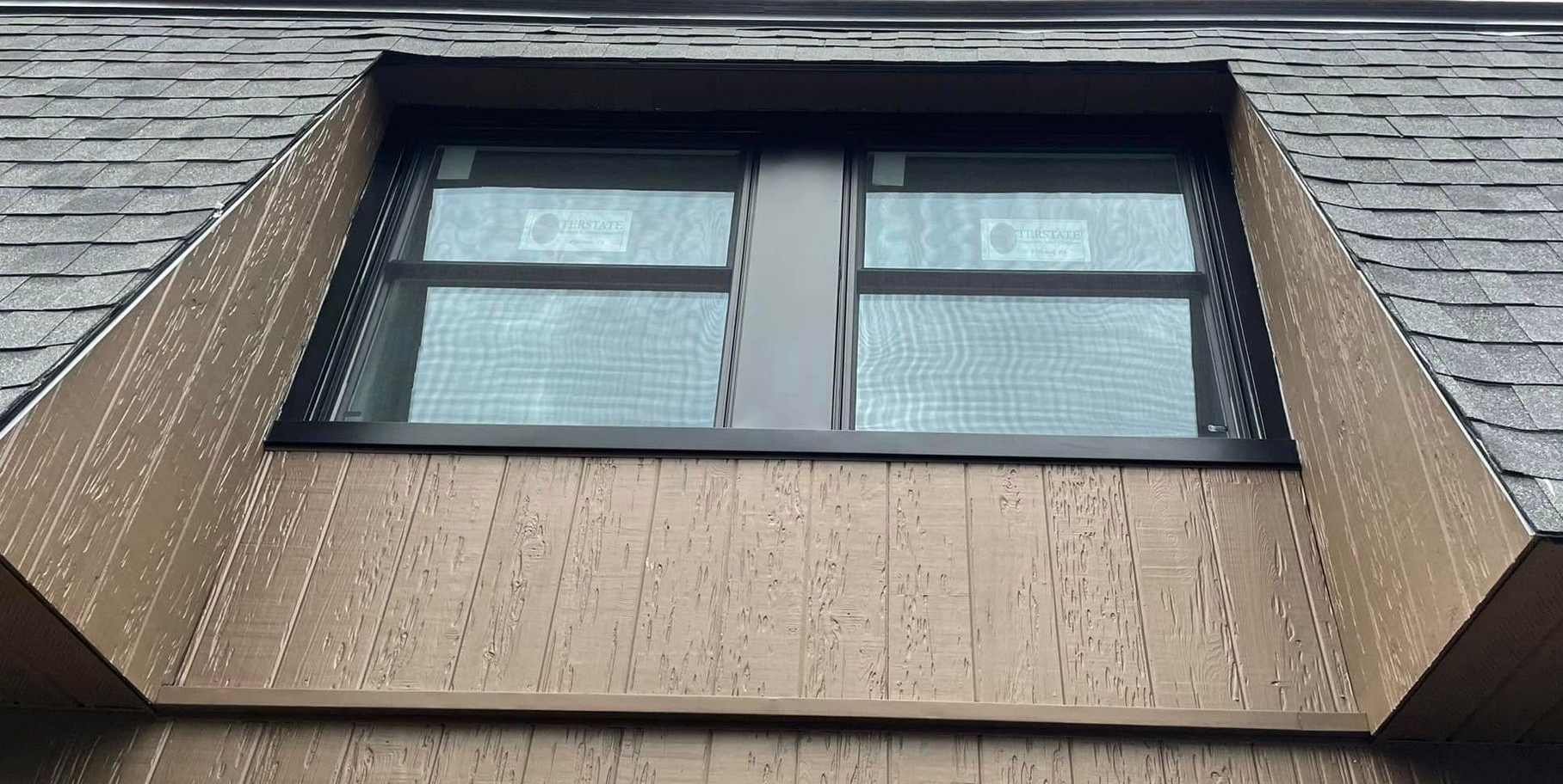 Tilted view of a black-framed window on a brown brick building facade