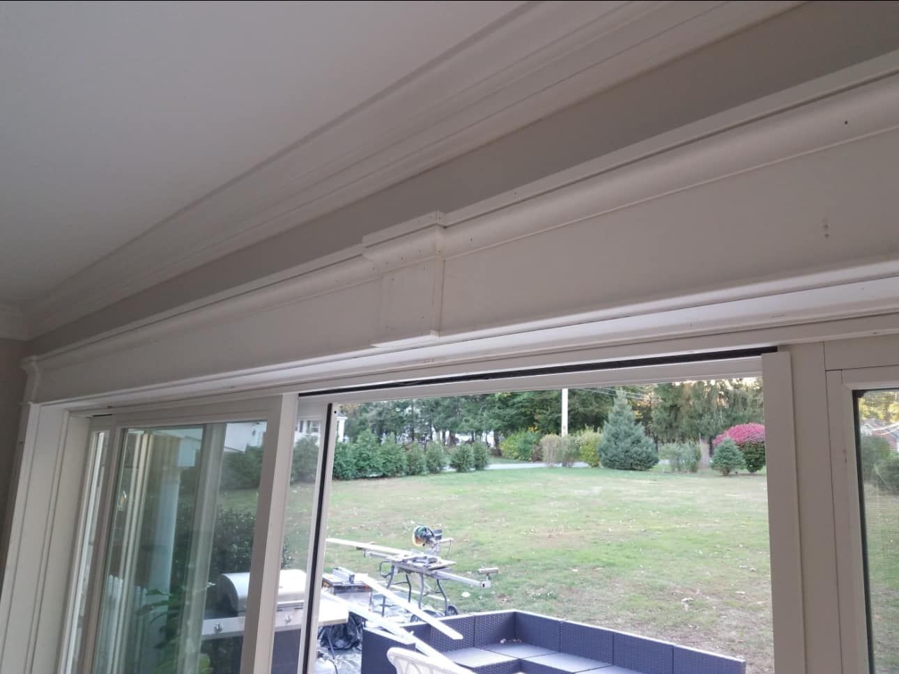 White sliding glass door with a decorative trim, overlooking a backyard.