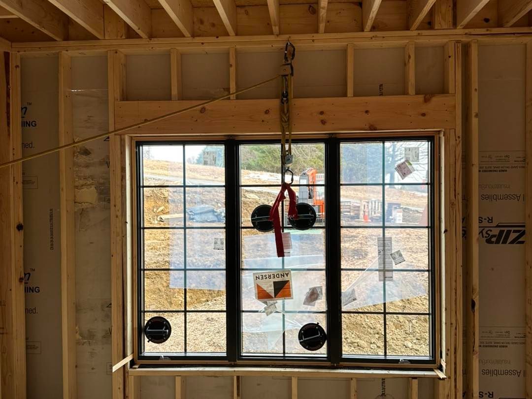 Window installation in new construction. Black framed window with suction cups, wooden framing visible.