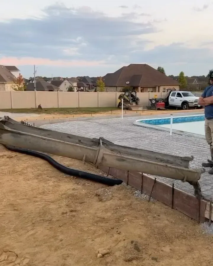 Collapsed backyard pool wall beside a blue pool, with dirt and debris in a suburban yard.
