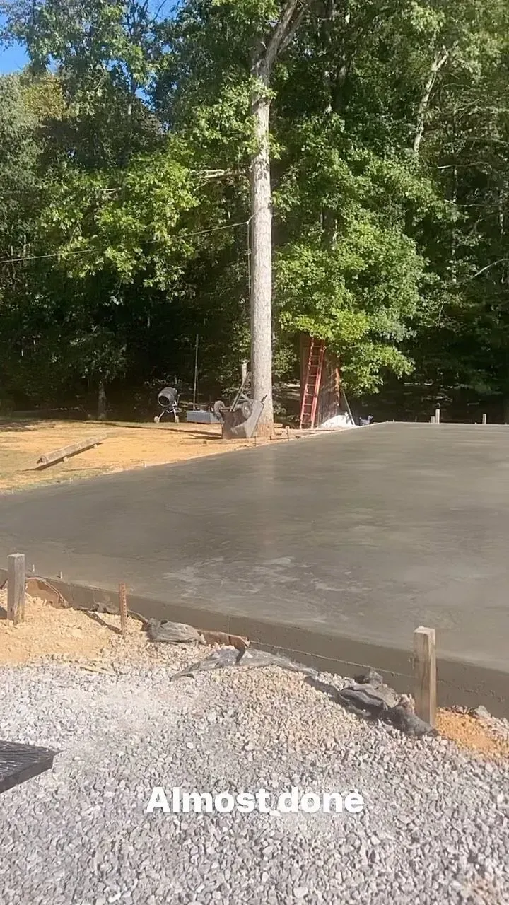 Fresh concrete slab being poured beside a wooded area, with “Almost done” text at the bottom.