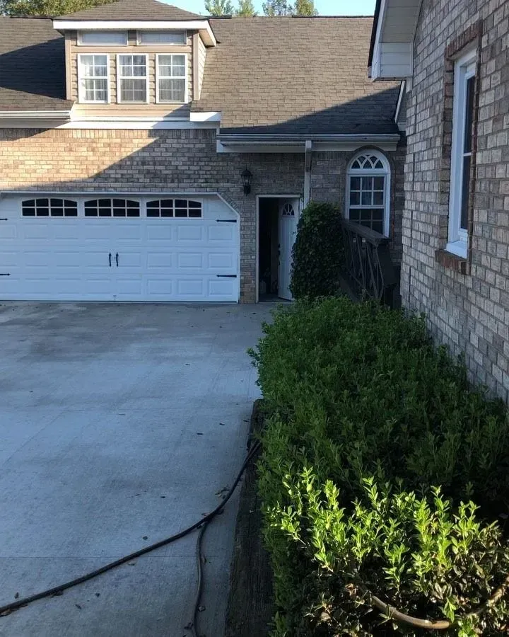 Covered porch with wet stamped concrete floor, wooden posts, and a white door on a gray house