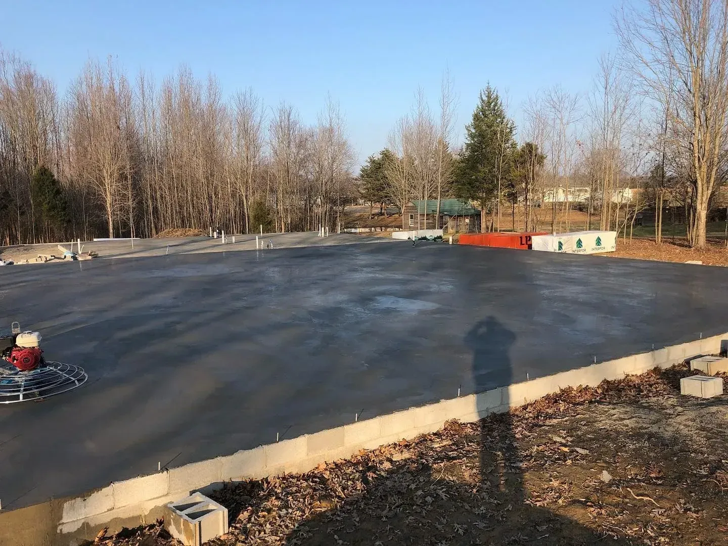 Freshly paved asphalt court bordered by leafless trees under a clear blue sky