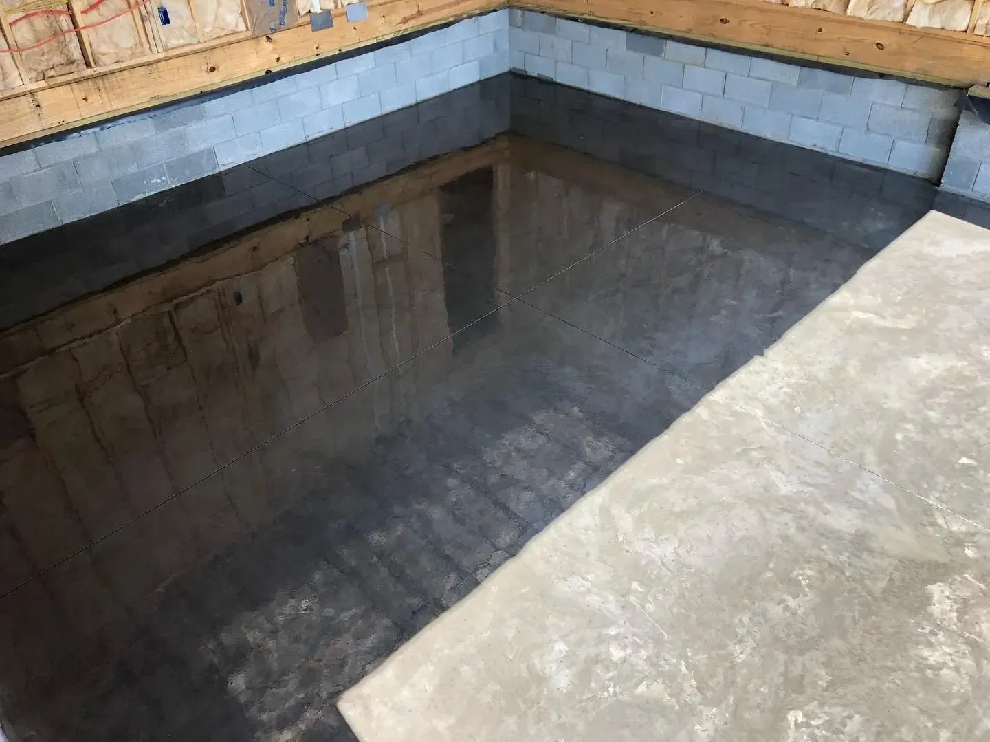 Concrete water tank corner with shallow standing water and brick walls