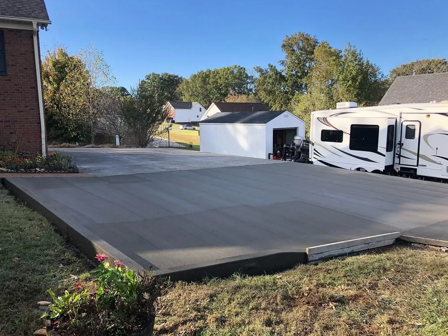 Concrete driveway slab beside a house, garage, and parked RV in a suburban yard