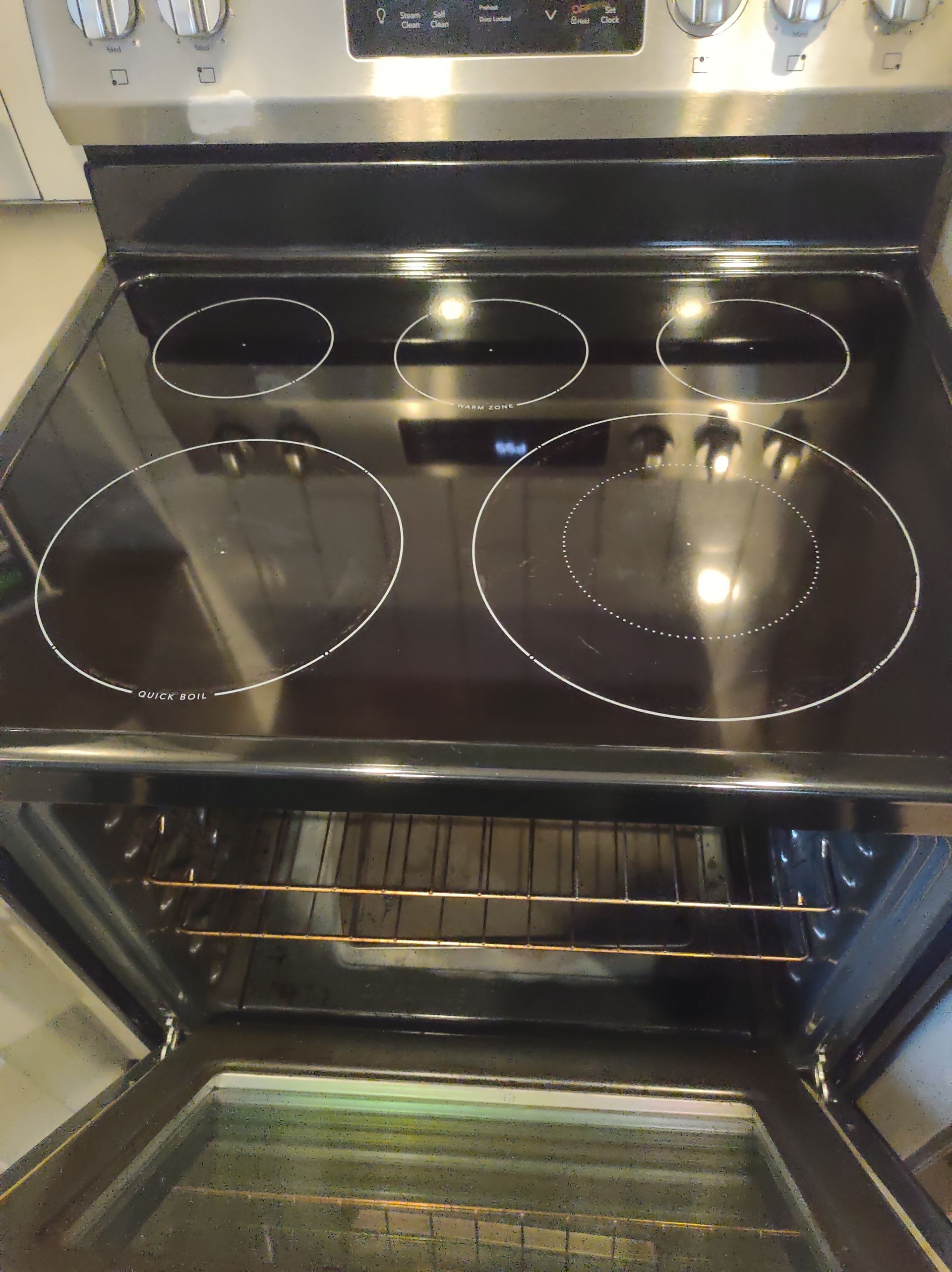 Black electric stovetop with four burners, oven door open. Silver oven exterior.