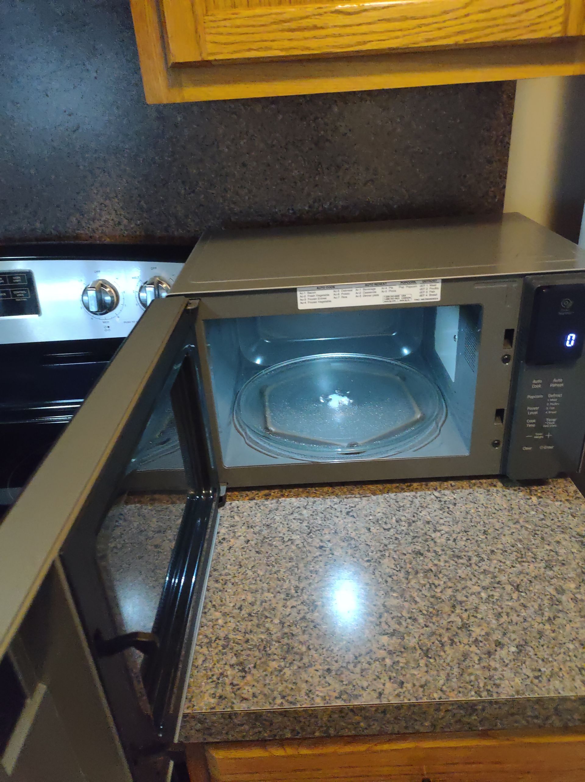 Opened microwave on a countertop with a stove in the background.