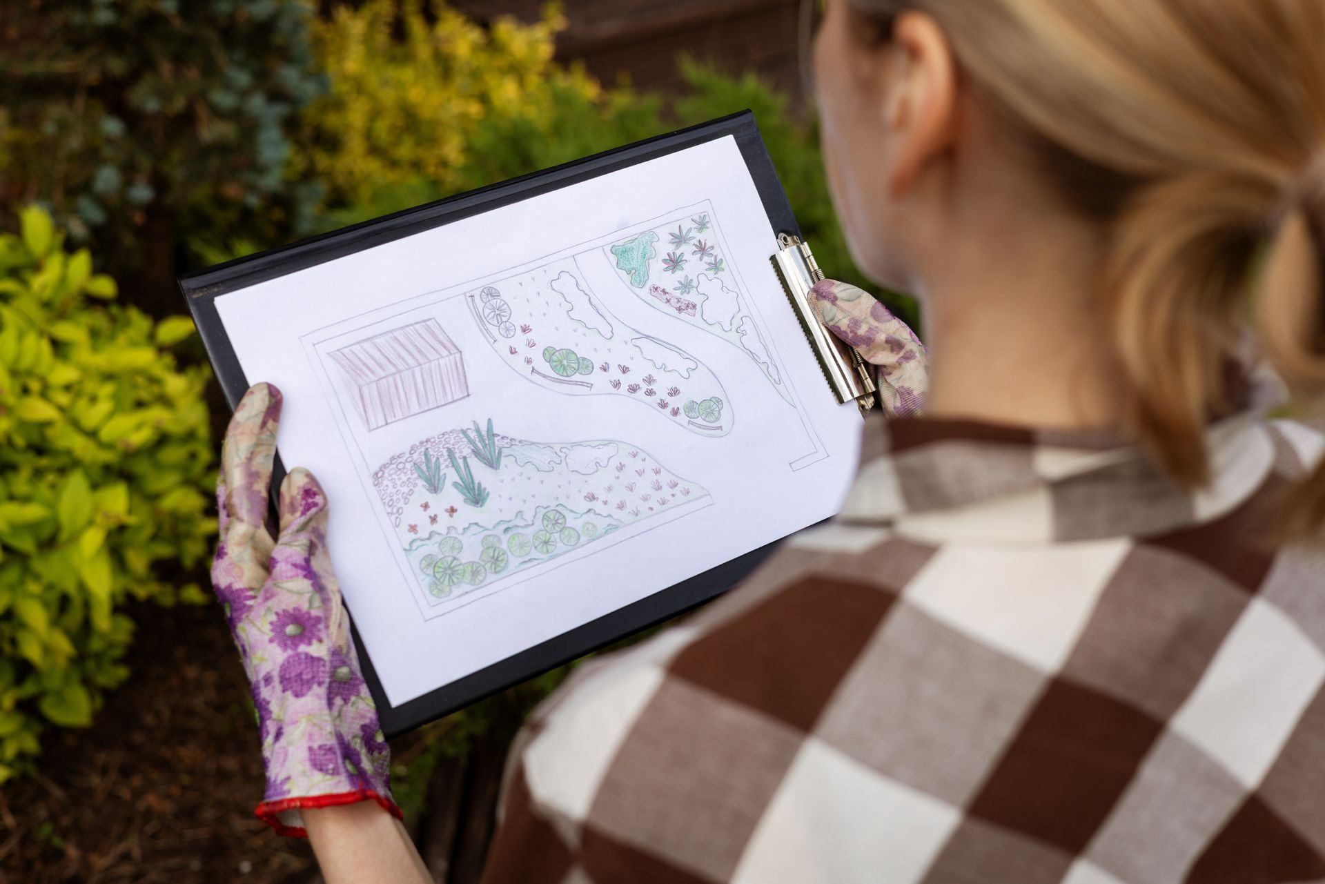 Woman gardener looking at home backyard garden plan.