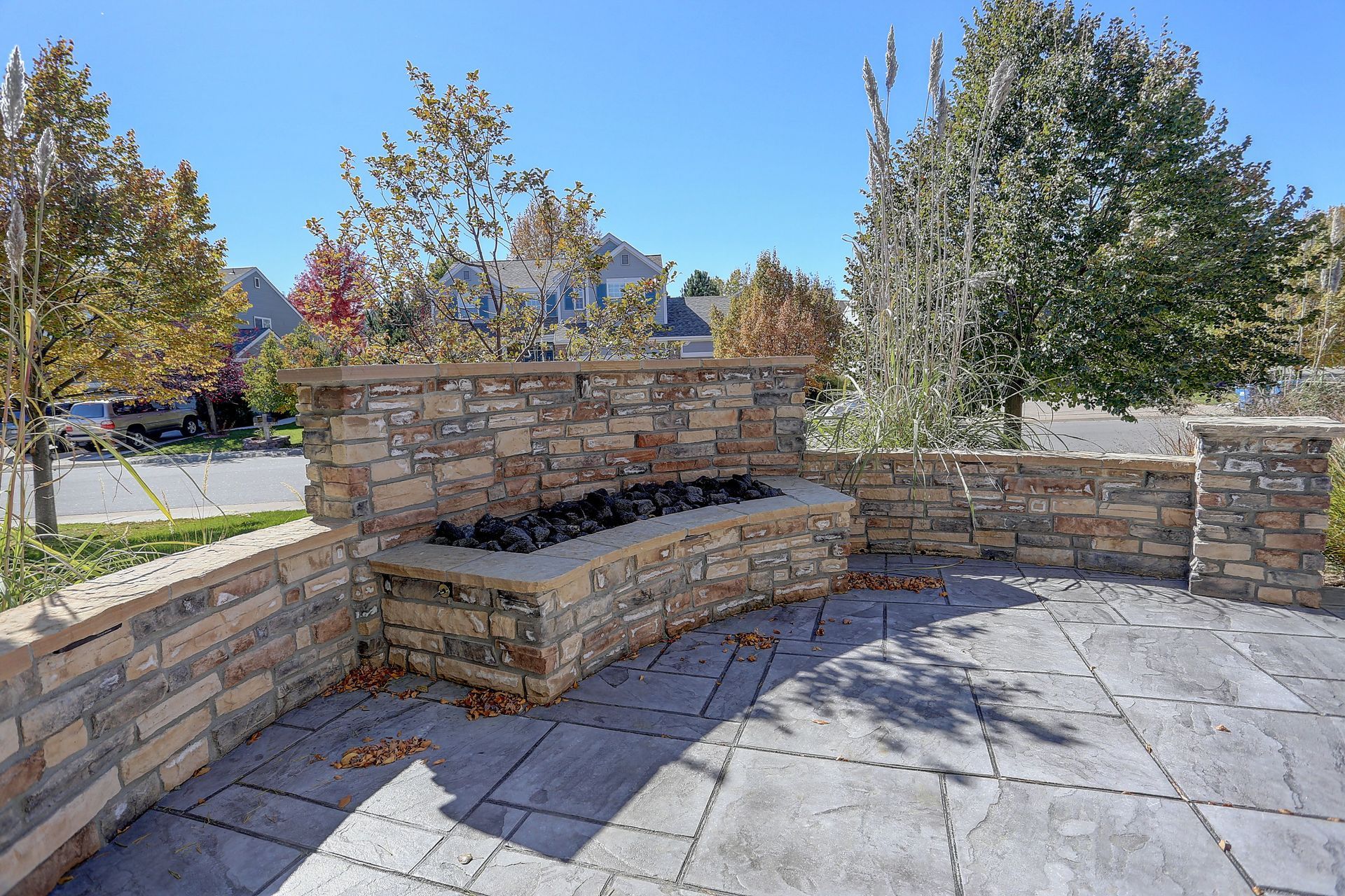 Hardscape patio with a stone fire pit and landscaped seating area