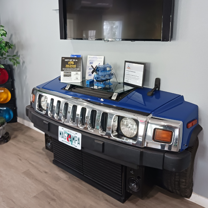 Blue Hummer display in a showroom, with framed awards and a TV mounted above it
