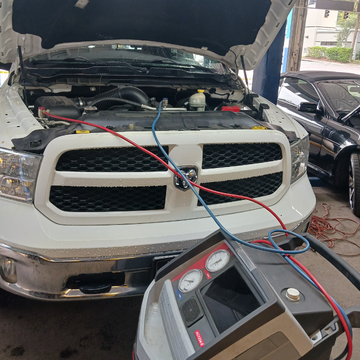 Person holding a red car diagnostic scanner near an open engine bay