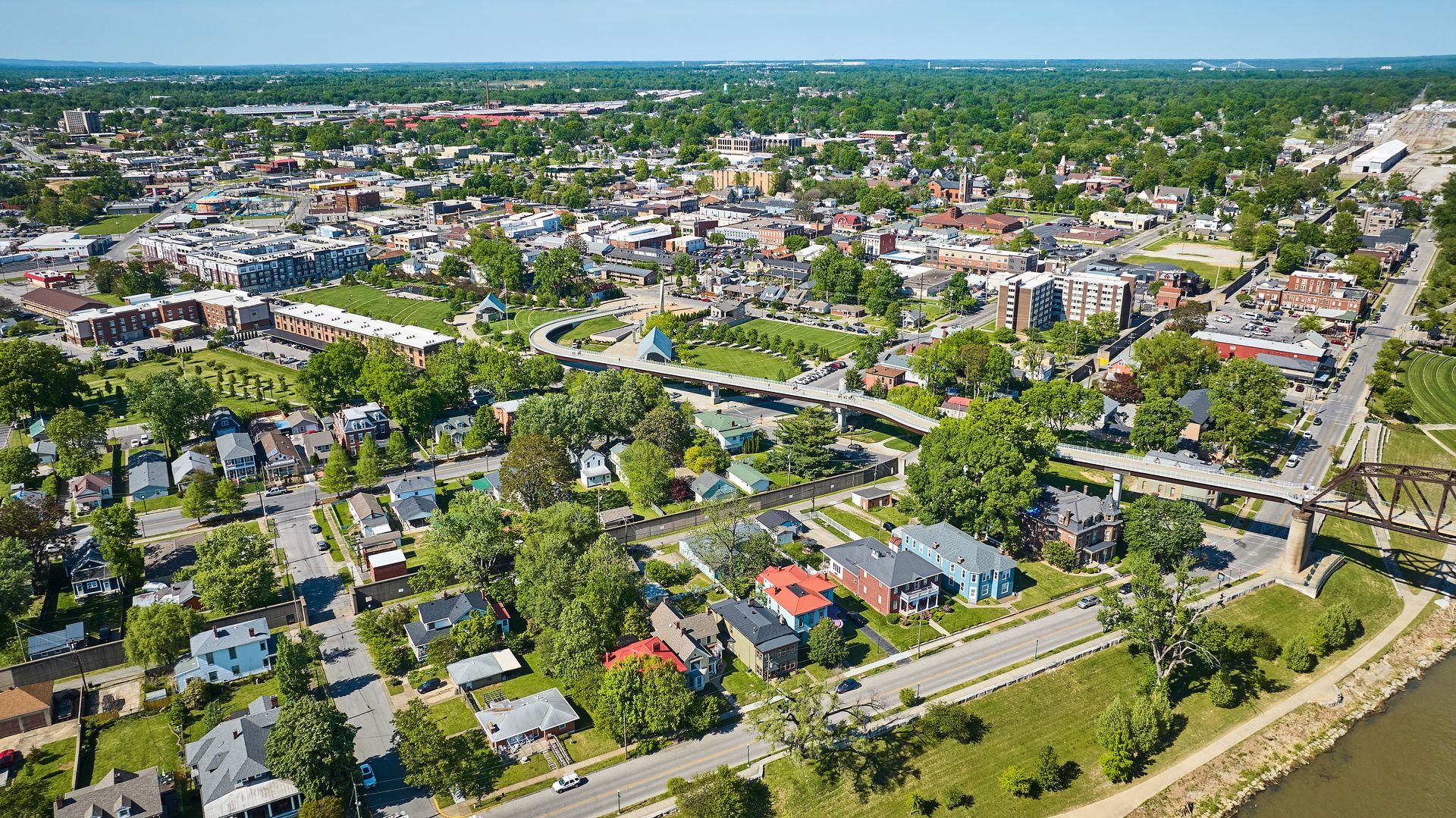 An aerial view of a city surrounded by trees and a river.
