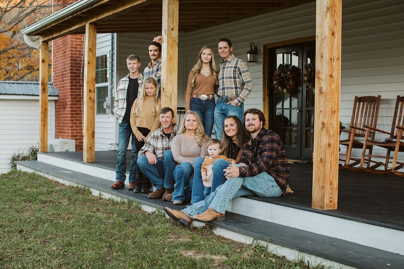 A large family is posing for a picture on the porch of their house.