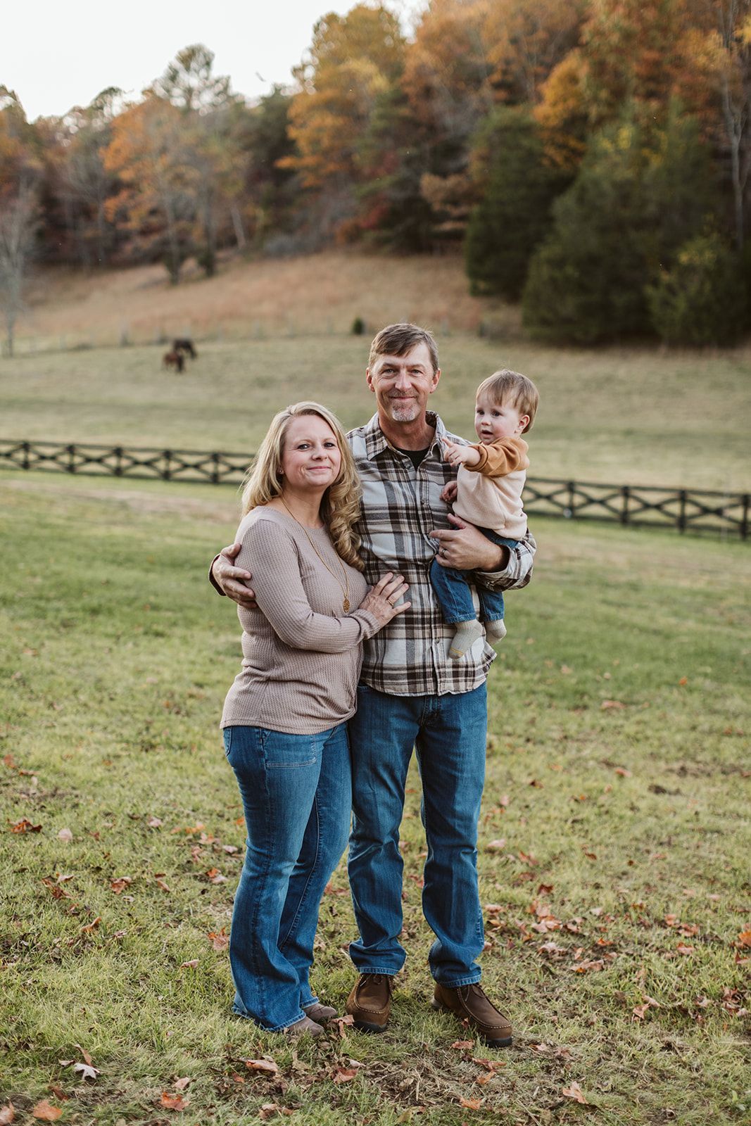 A man and woman are holding a baby in a field.