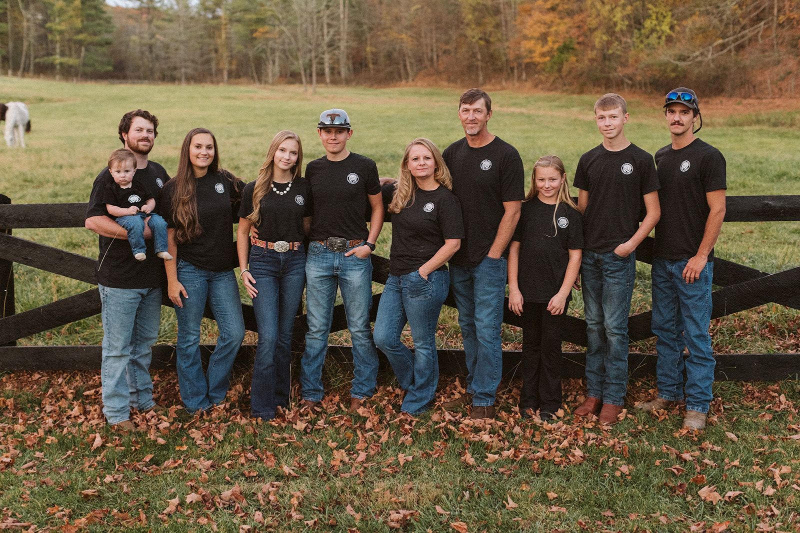 A group of people are posing for a picture in front of a fence in a field.