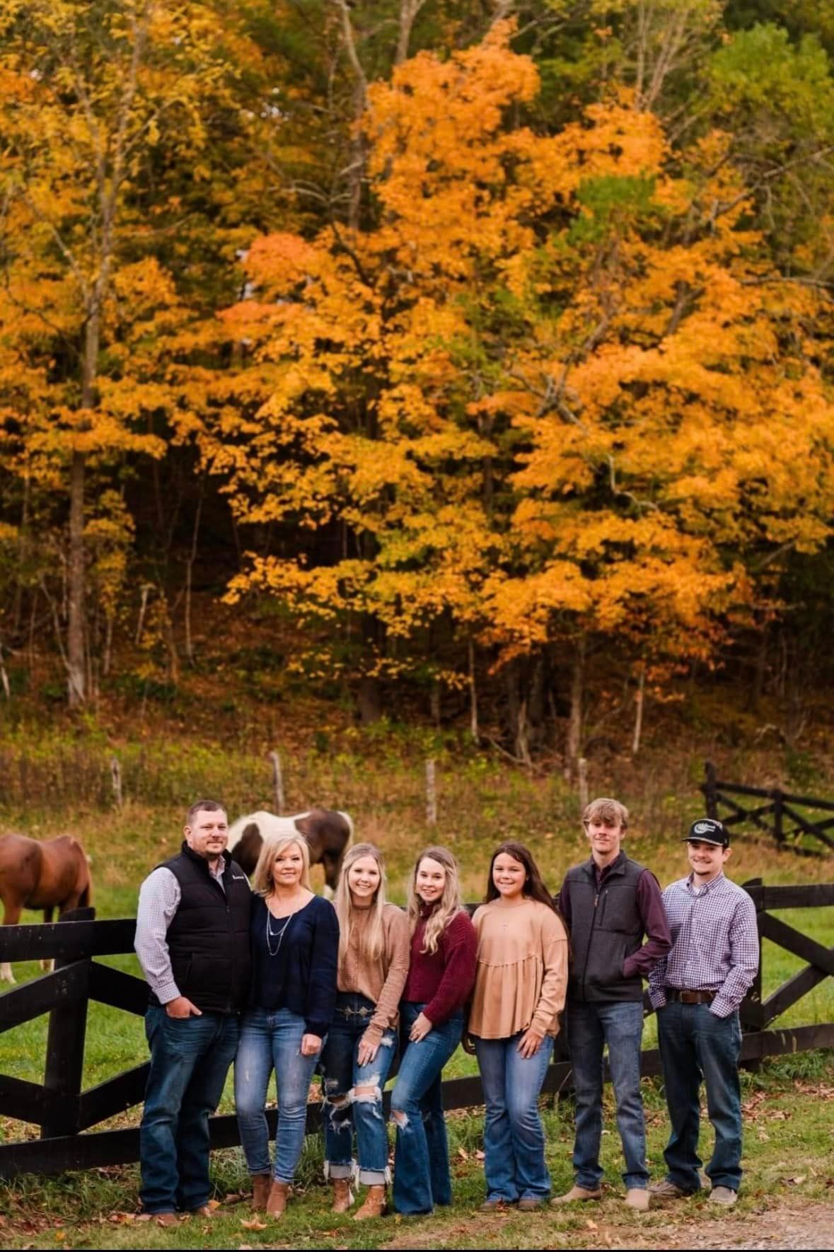 A group of people are posing for a picture in front of a horse.
