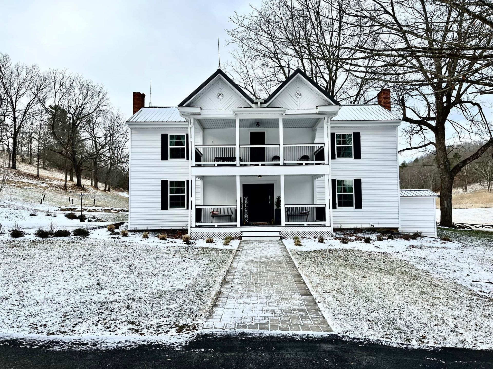 A large white house with a porch in the snow