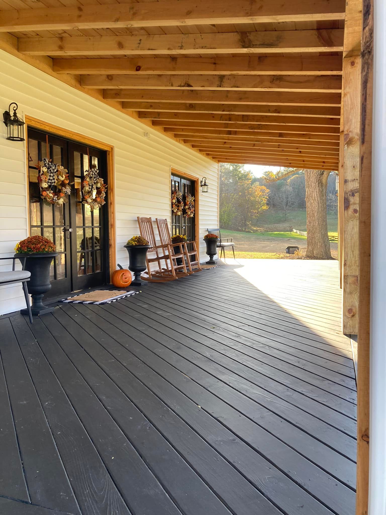 A porch decorated for fall with rocking chairs and pumpkins
