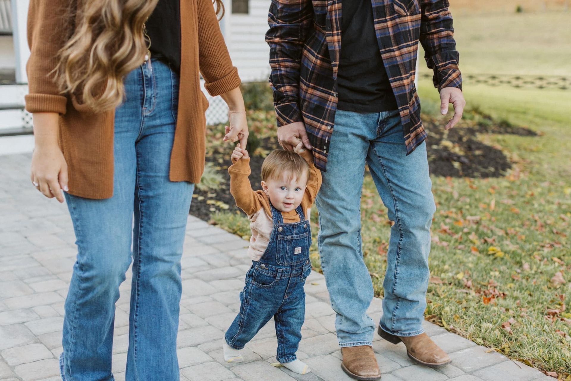 A family is walking down a sidewalk holding hands.