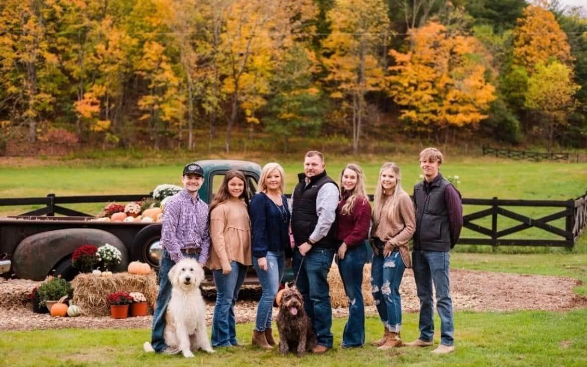 A group of people and a dog are posing for a picture in front of a truck.