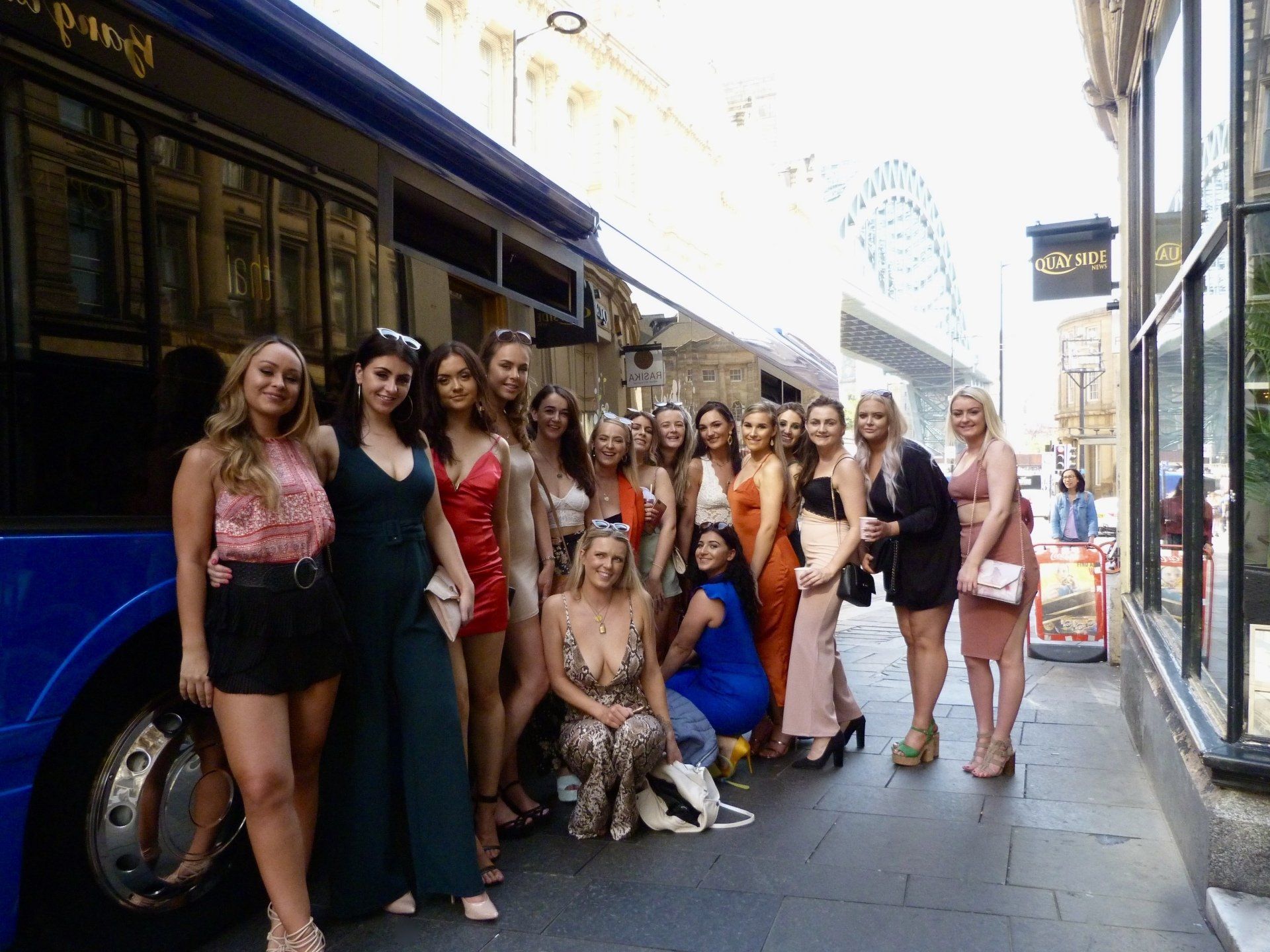 A group of women are posing for a picture in front of a blue bus.