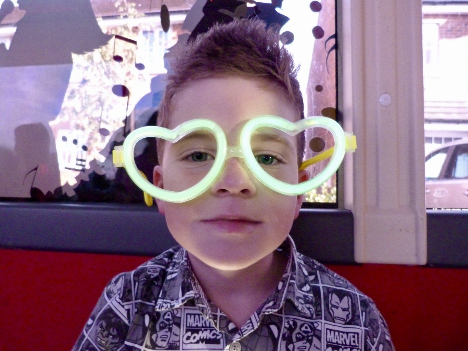 A young boy wearing glow in the dark heart shaped glasses