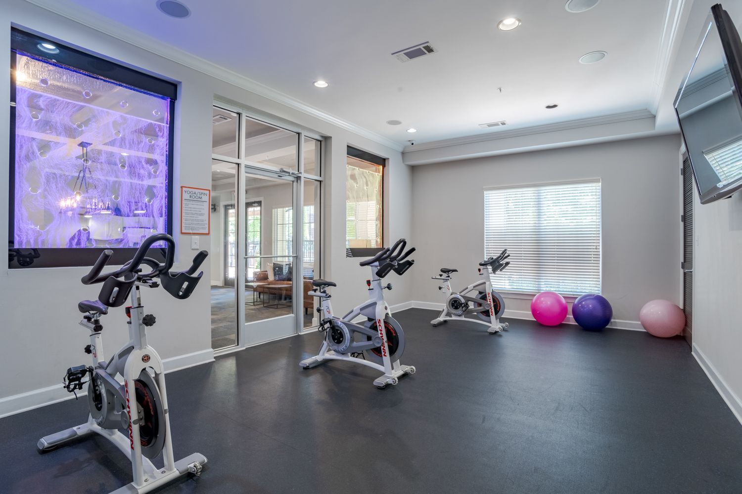 Gym with spin bikes, exercise balls, and a view into another room at The Vive at Kellswater.