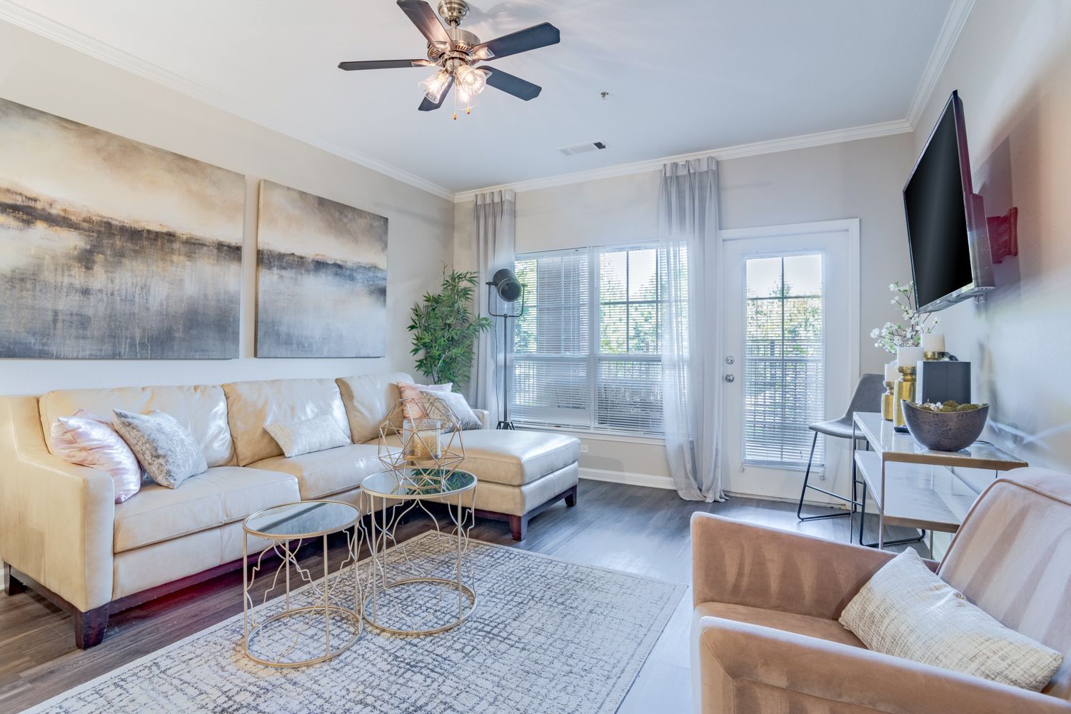 Cozy living room with cream-colored couch, glass coffee table, and large artwork above the sofa at The Vive at Kellswater.