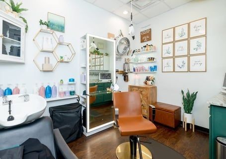 Salon interior with styling chair, mirror, shampoo bowl, and shelves with products.