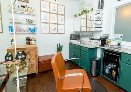 Hair salon interior with orange chair, green cabinets, and product display.