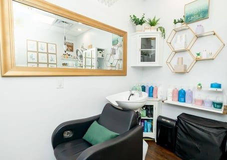 Salon interior with chair, sink, mirror, and shelves displaying products.