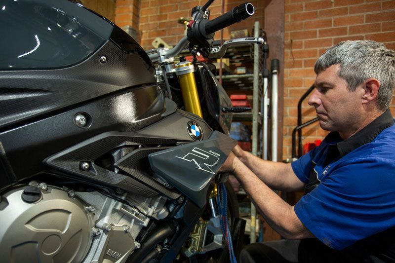 A Man Is Working on A Motorcycle in A Garage — Lismore Car Repairs in Lismore, NSW