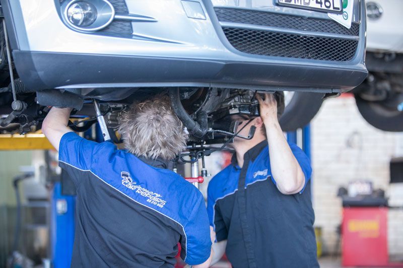 Two Men Are Working Under a Car in A Garage — Lismore Car Repairs in Lismore, NSW