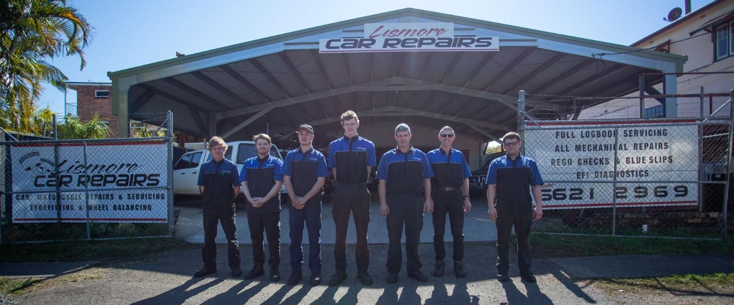 A Group of Men Are Posing for A Picture in Front of A Garage — Lismore Car Repairs in Lismore, NSW