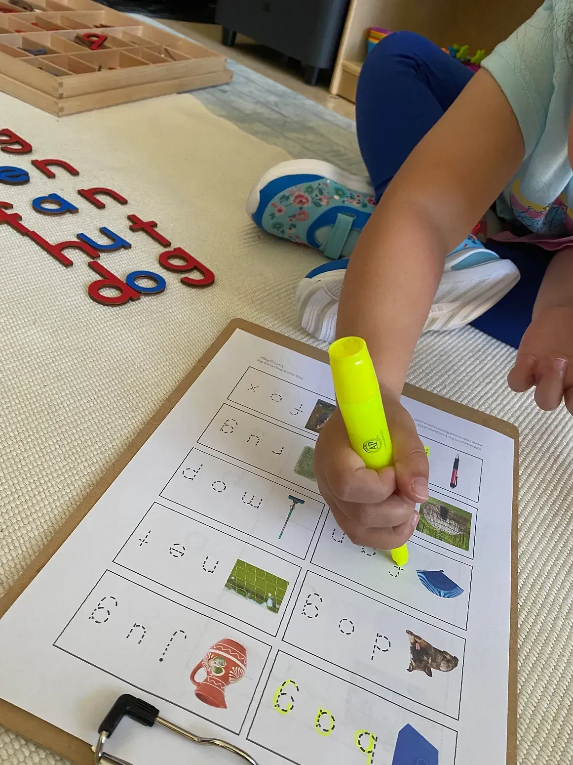 A child is writing on a clipboard with a yellow marker