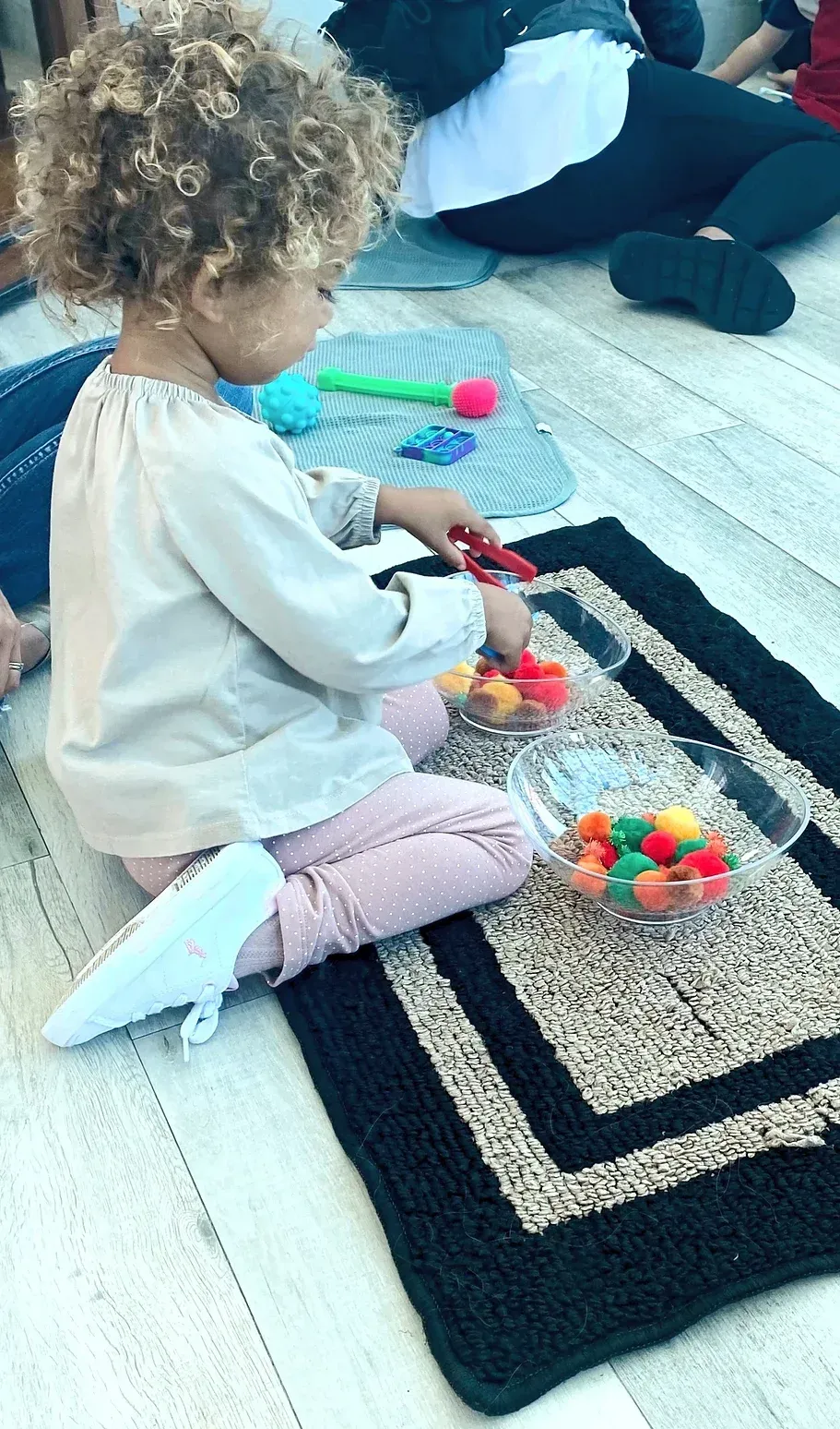 A little girl is sitting on the floor playing with toys.