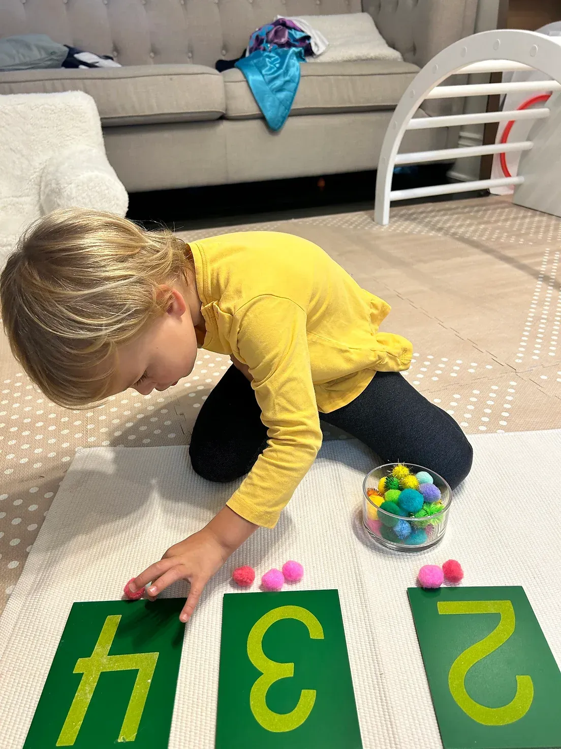 A little girl is playing with numbers on the floor