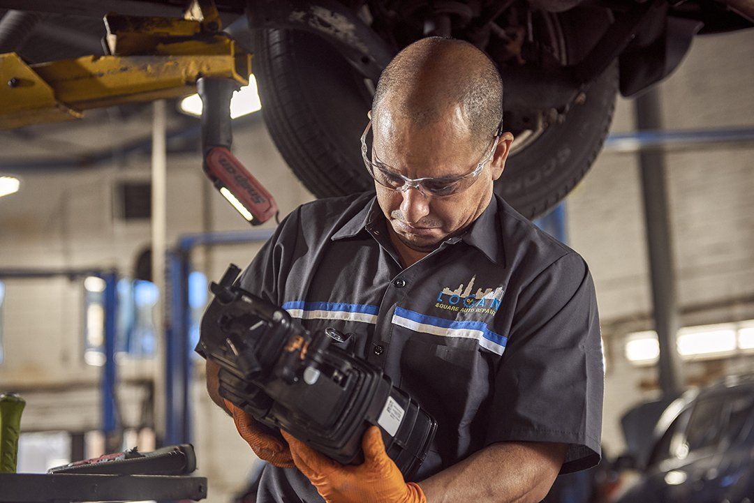 A man is working on the underside of a car in a garage.