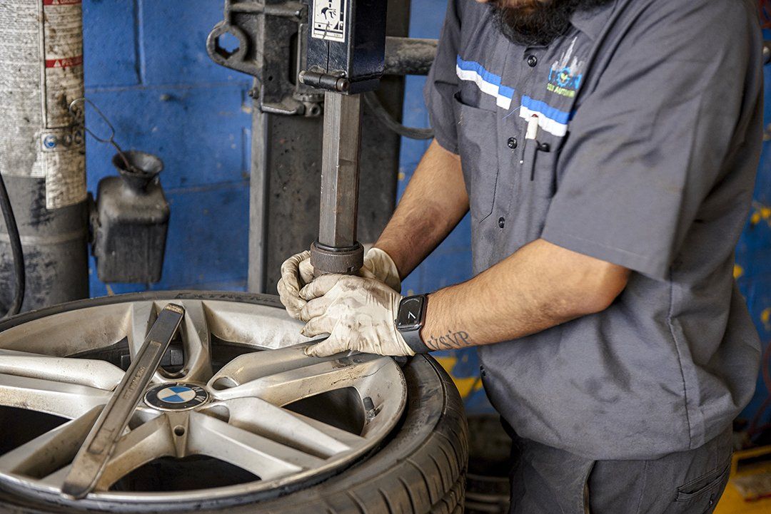 A man is changing a tire on a machine in a garage.