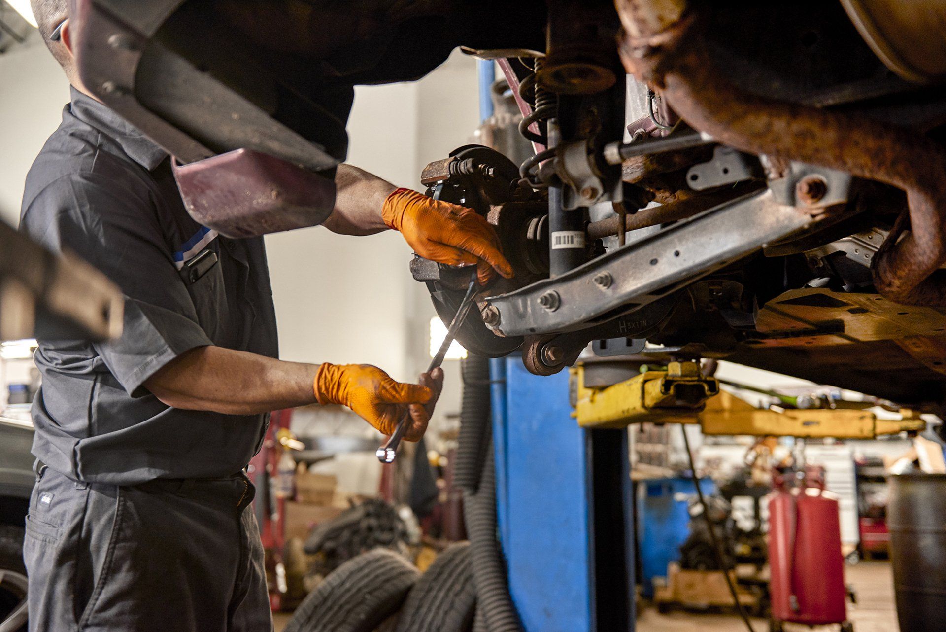 A man is working on a car on a lift in a garage.