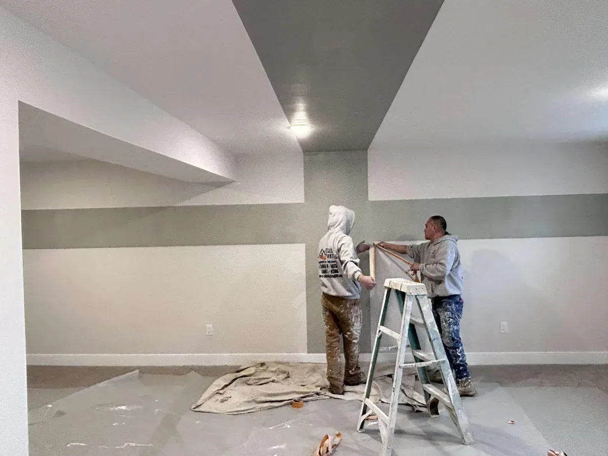 Two painters from Oasis Painting & Drywall LLC working in Philadelphia, PA, painting a room with white and green